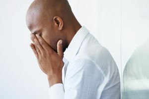 A young businessman crying with his face in his hands