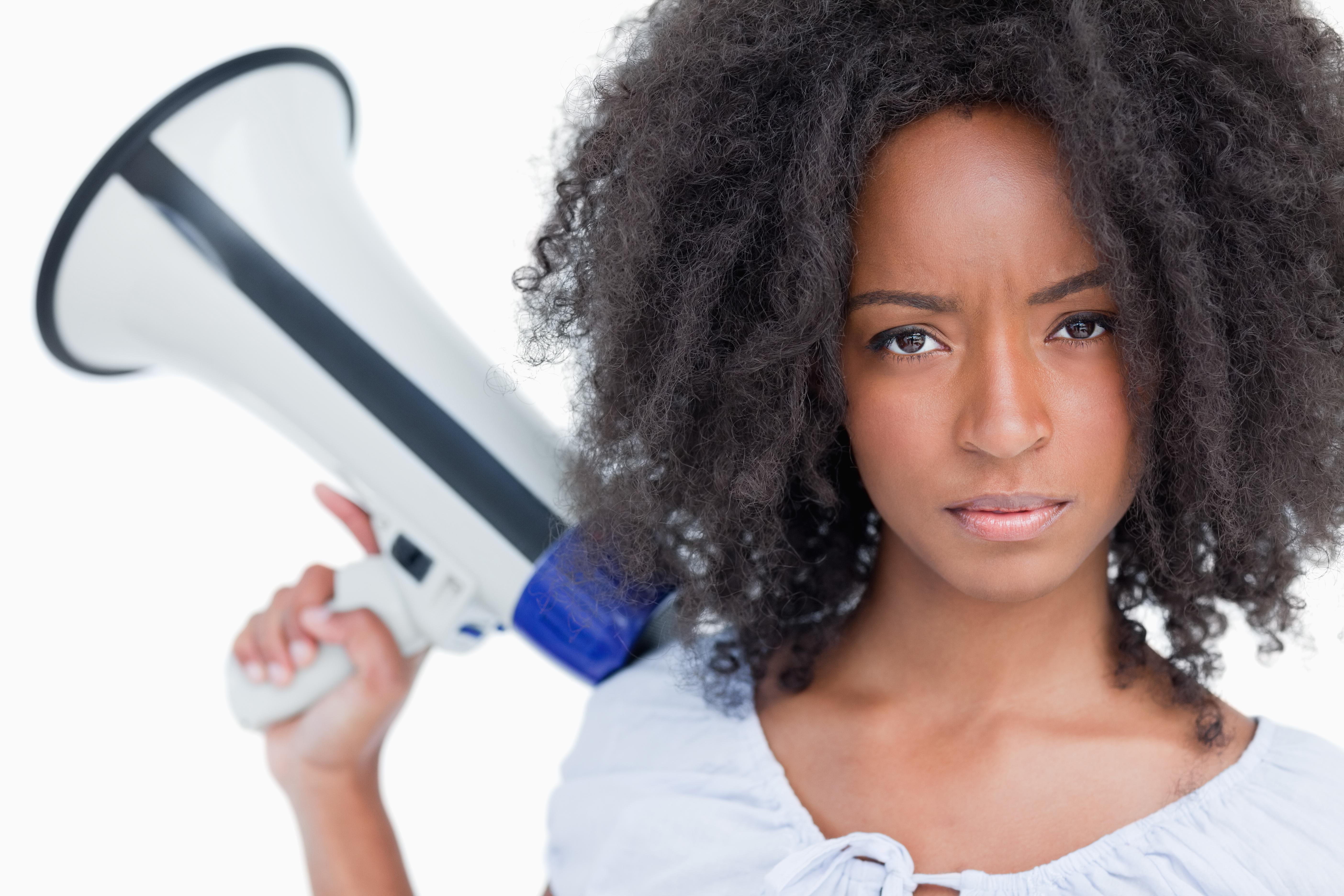 Young serious woman holding a megaphone behind her