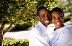 Black African American couple happy together in sunshine at home together in yard and snuggling