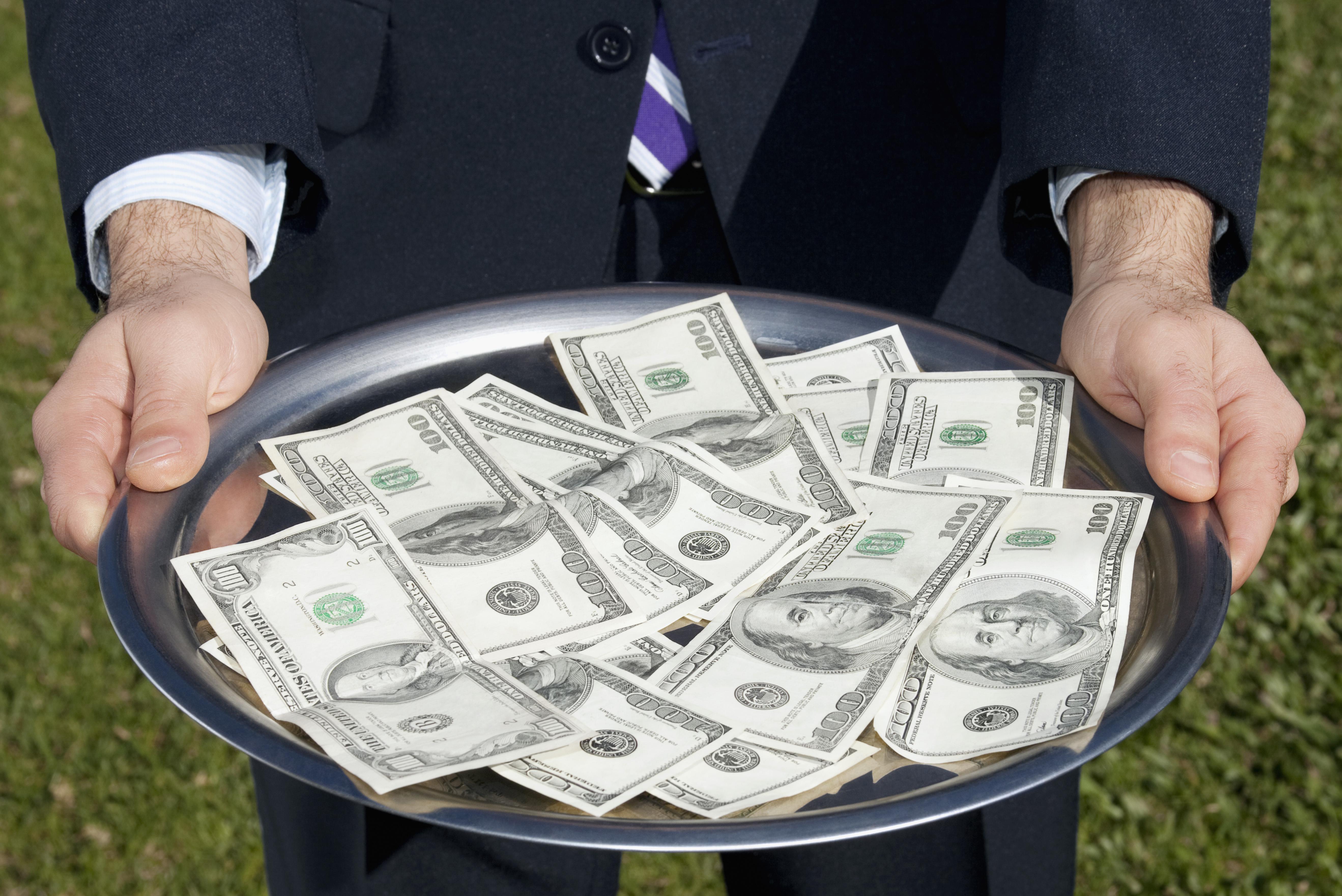 Businessman holding US currency notes on a plate