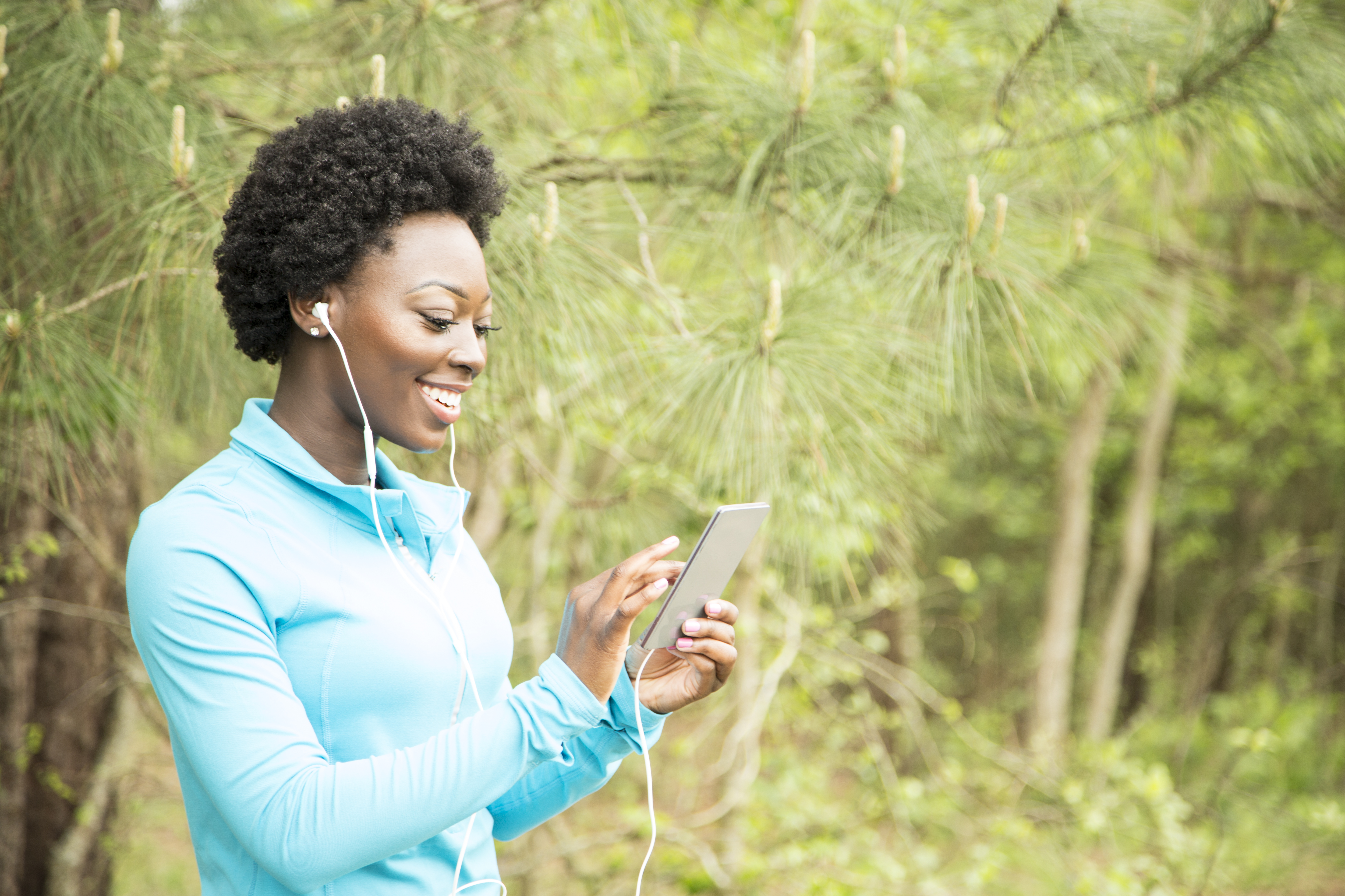 One African descent woman exercising, using cell phone in neighborhood park.