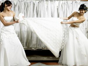 Young women in fitting room tugging at gown