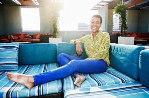 Black woman laughing on rooftop sofa