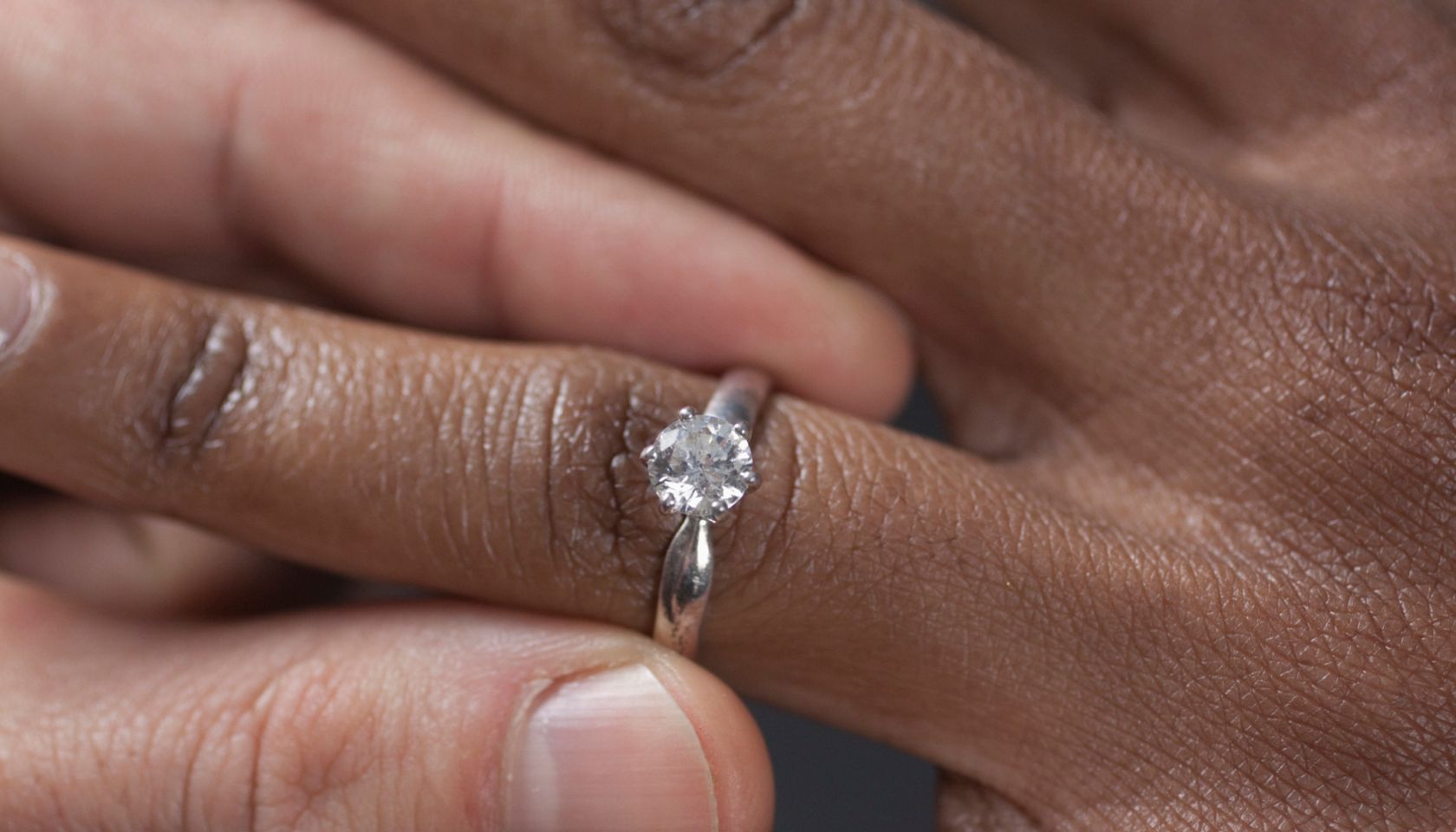 Close up of man putting engagement ring on girlfriend