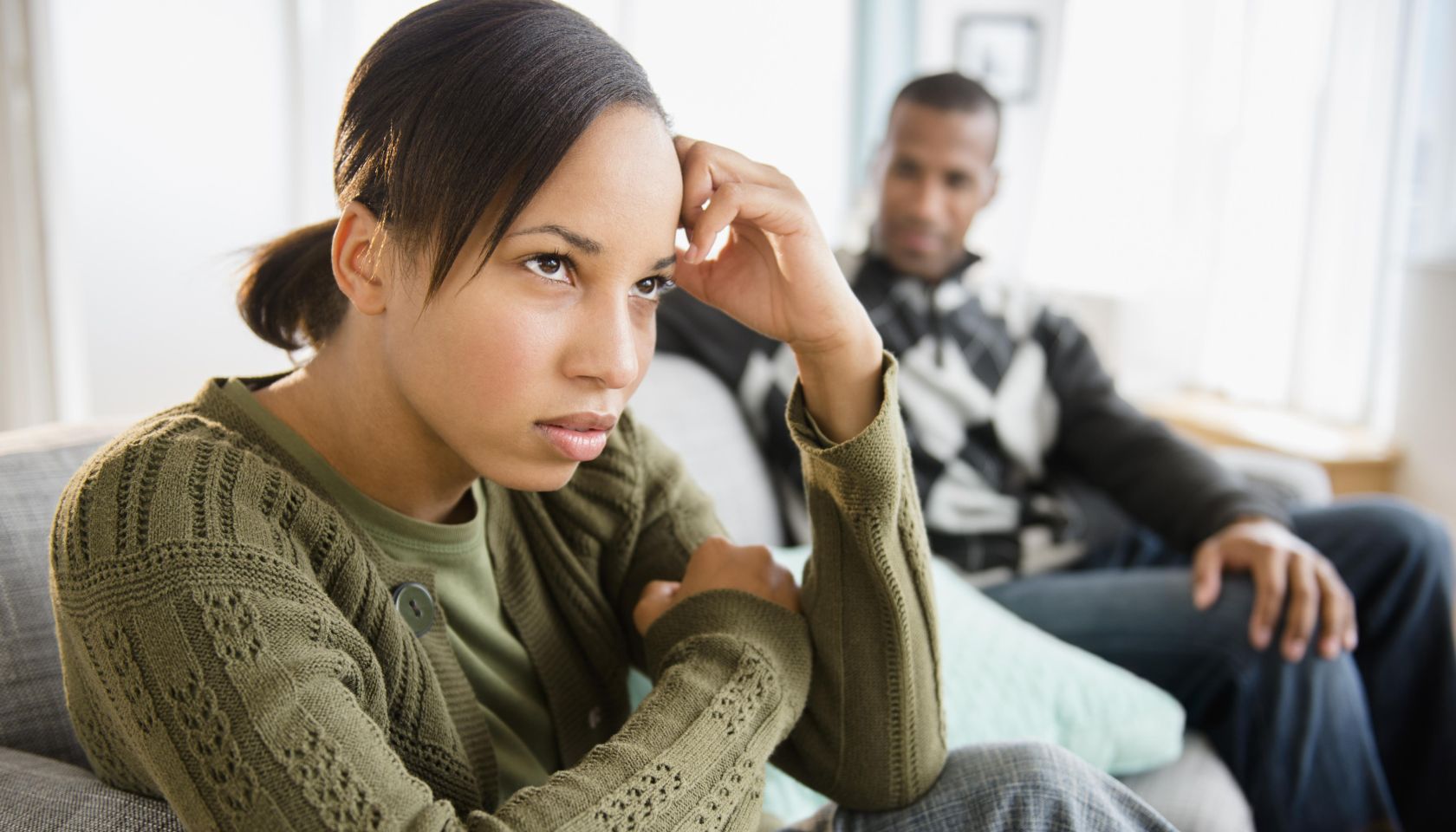 Boyfriend watching frustrated girlfriend on sofa