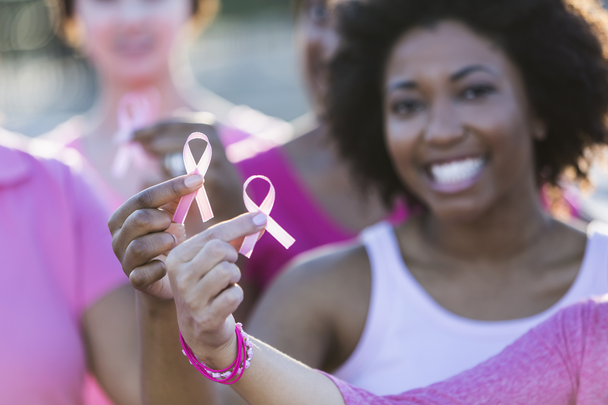 Multiracial women holding breast cancer awareness ribbon