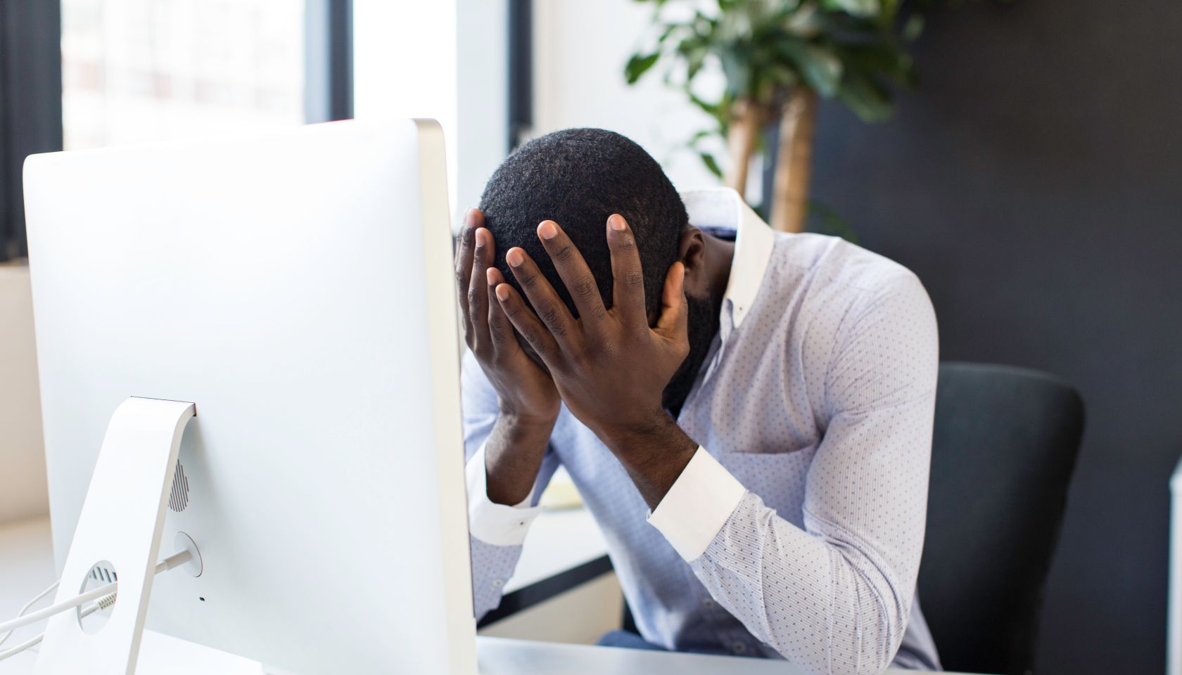 Stressed african businessman sitting at his desk.