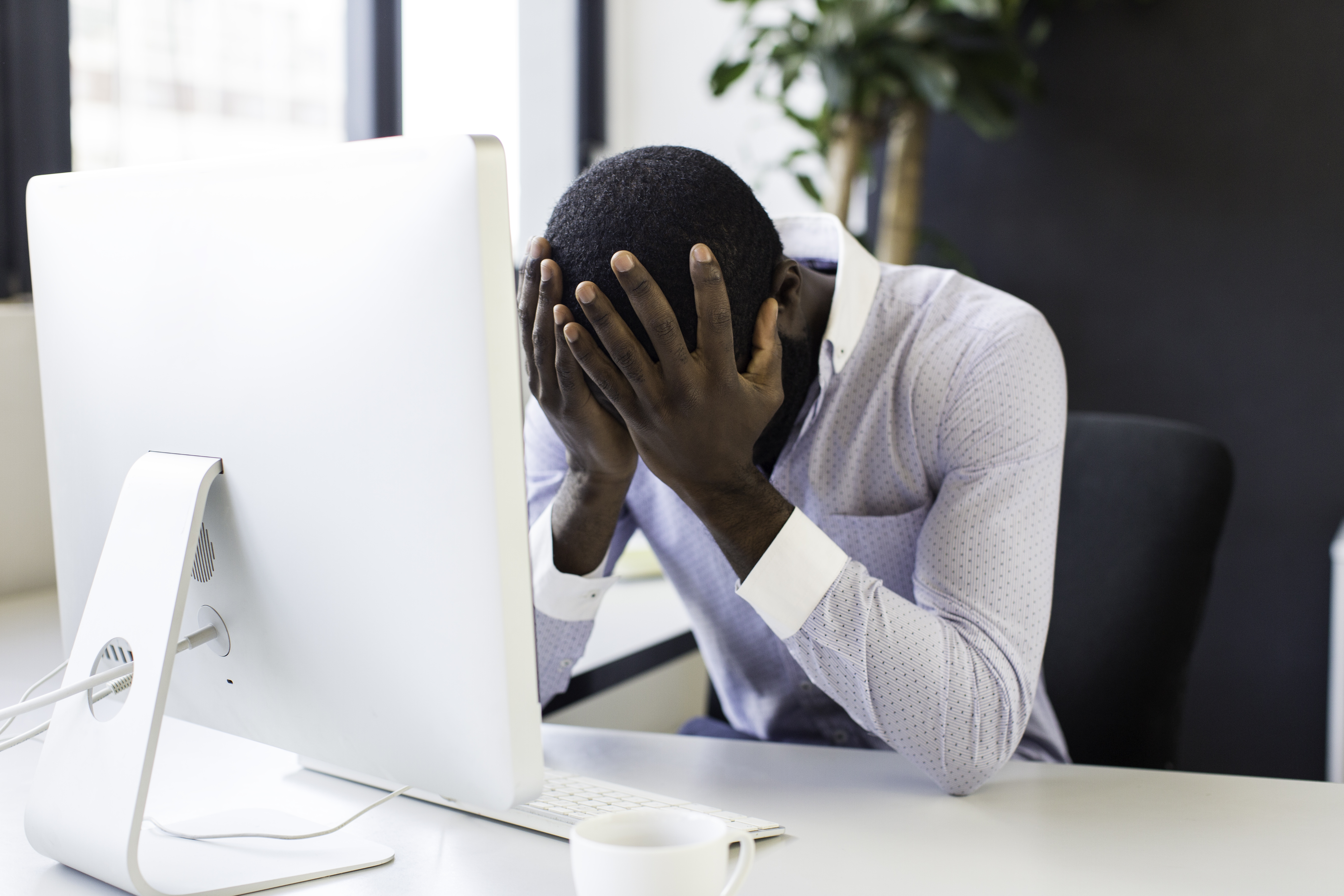 Stressed african businessman sitting at his desk.