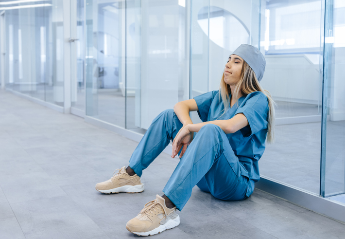 Tired Female Medical Professional Taking Break in Hospital Corridor