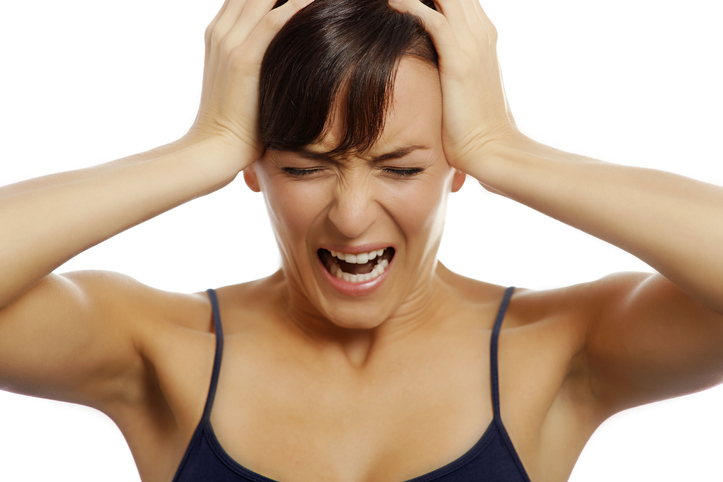 Young woman holding her head and screaming