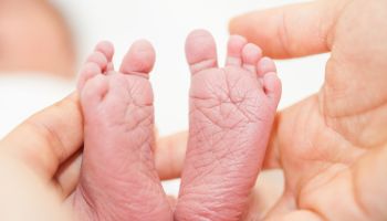 Closeup of a newborn feet and her father hands at hospital on the day of her birth