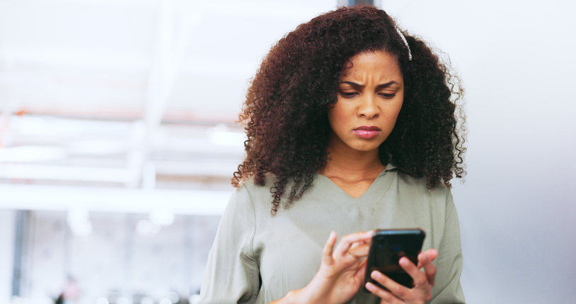 Sad, reading communication and black woman on mobile app, email and website with phone in an office. Frustrated, confused and business woman with a glitch on a mobile, internet stress and scam