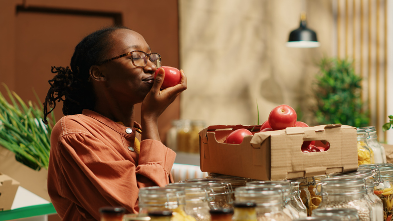 Vegan woman smelling fresh bio tomatoes from market crates