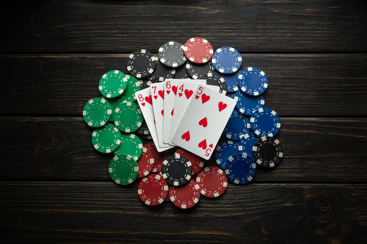 A pile of winning chips on a black table and playing cards lying on it with a winning combination in straight flush poker. Concept of luck in a casino or men club.